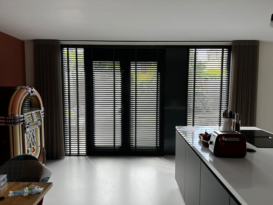 Zwarte houten jaloezieën door Rail Decor gemonteerd
